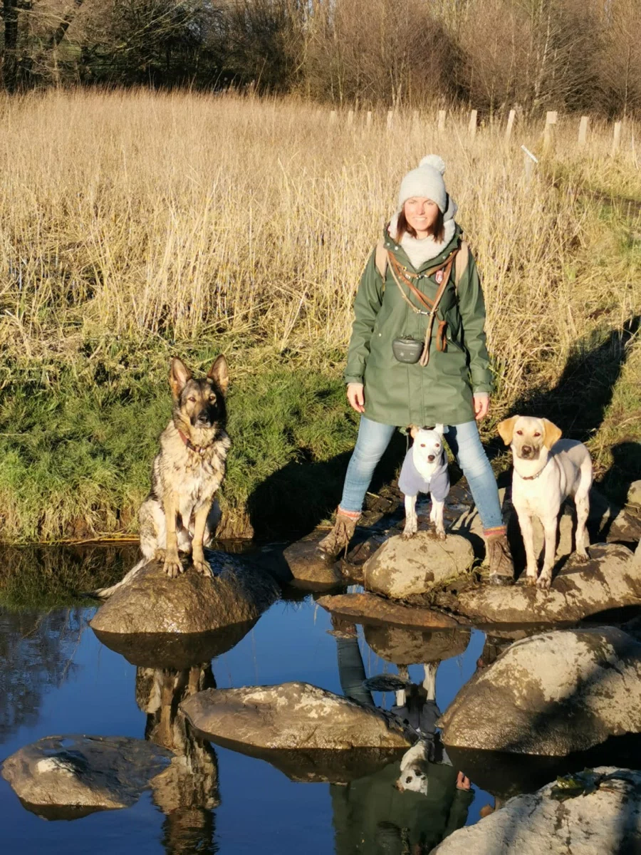Hanna auf steinen am teich mit ihren drei hunden
